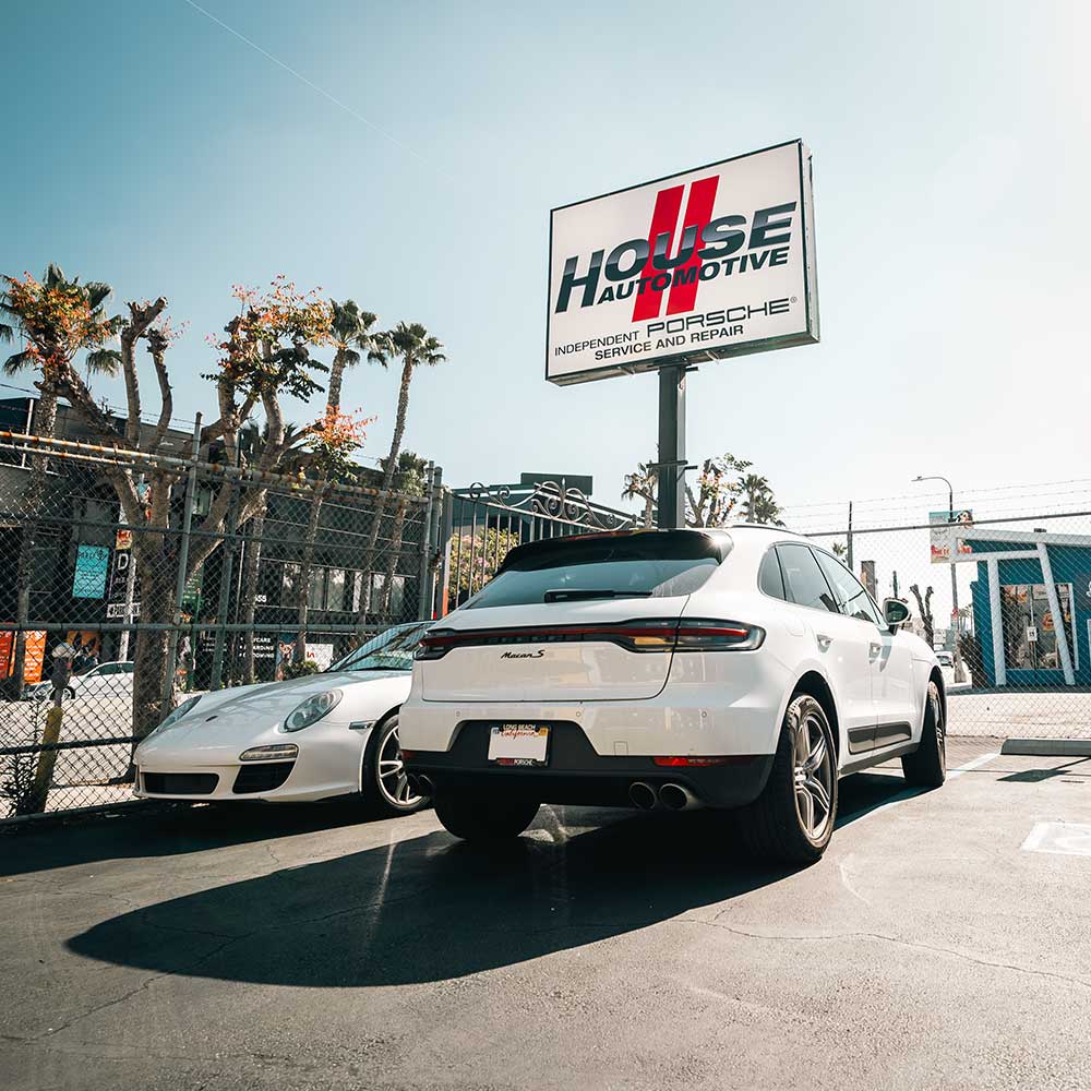 white porsche macan s and 911 at house automotive porsche service center