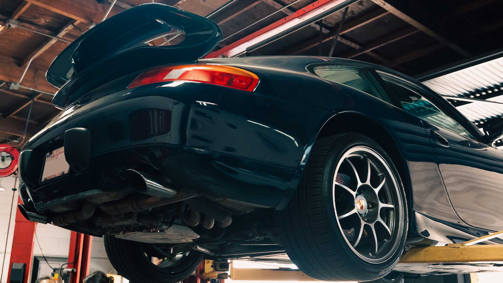 dark blue 996 porsche 911 c2 with factory aero kit getting pre purchase inspection on lift