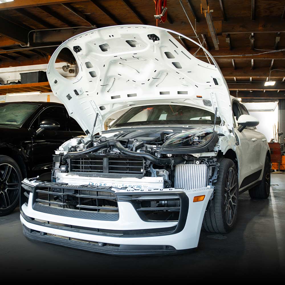 porsche macan with bumper off at body shop