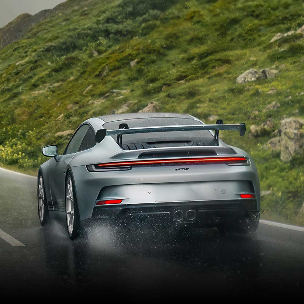 silver 992 gt3 driving on wet rainy mountain road