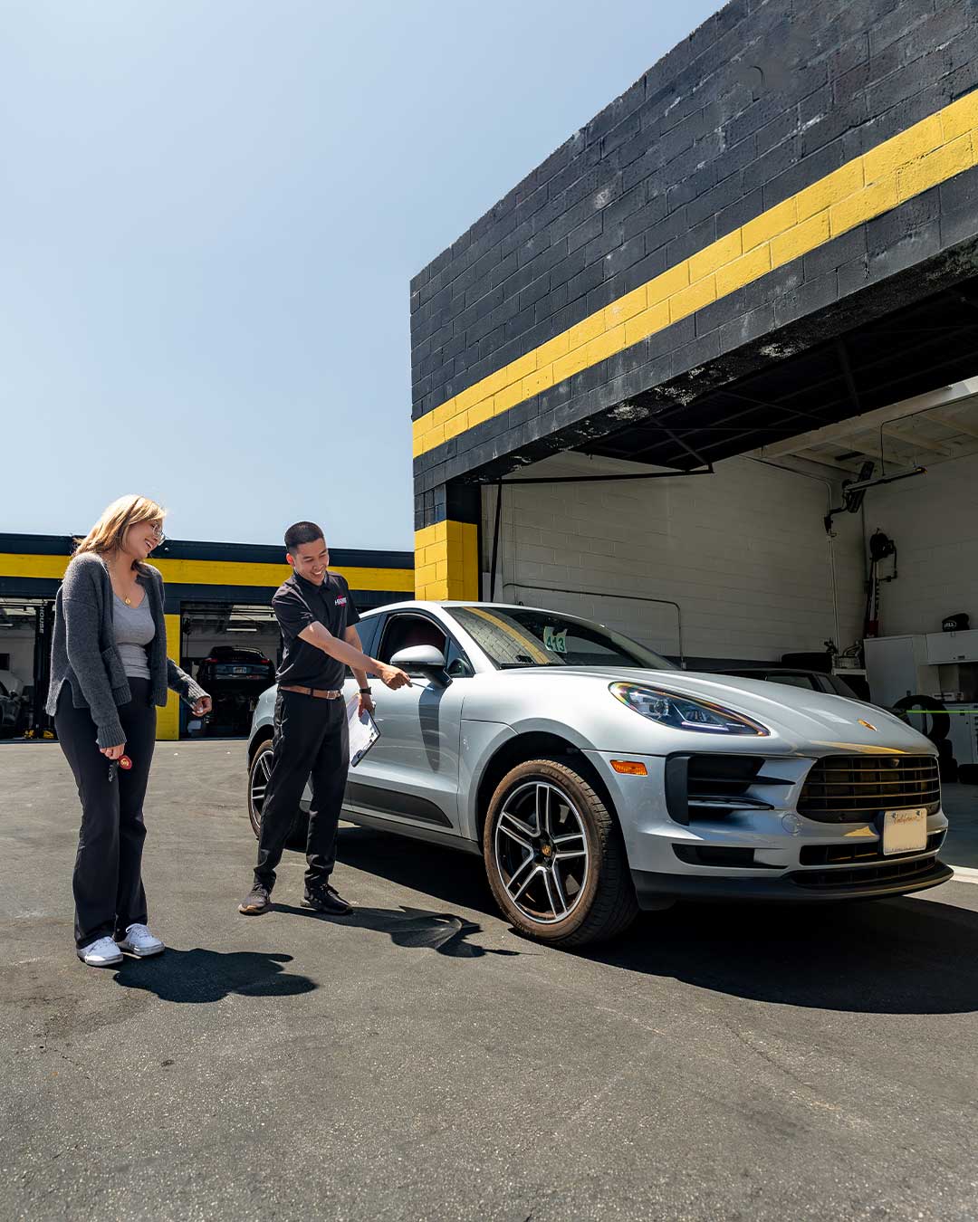 porsche macan service advisor explaining vehicle details to female customer at los angeles porsche service center