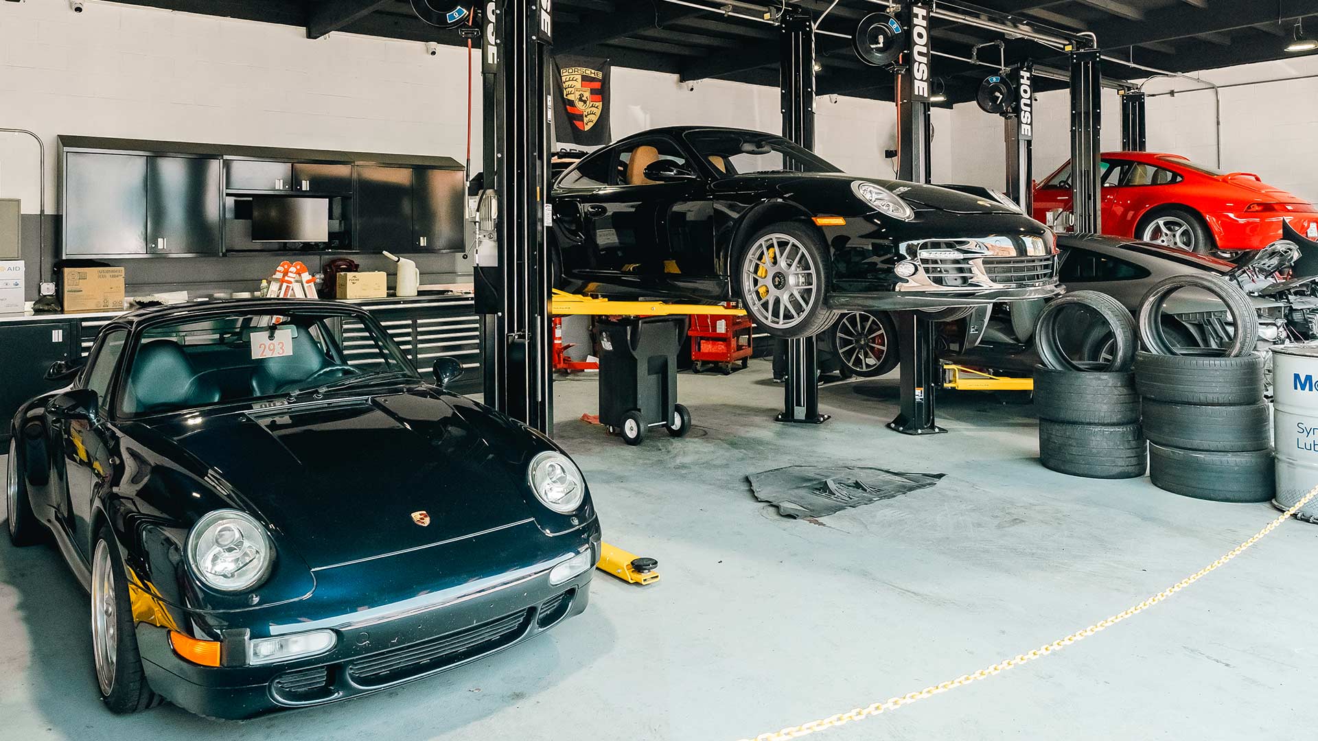 three porsche 911s from different generations in house automotive bay