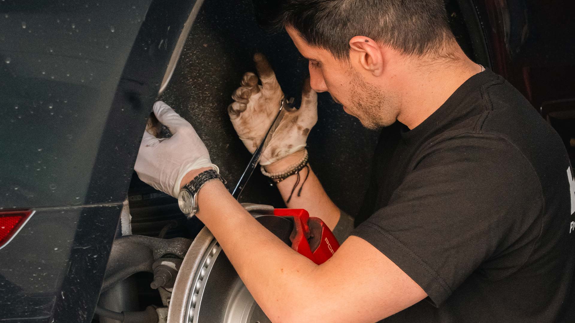 porsche service tech working on brake repair job on porsche car