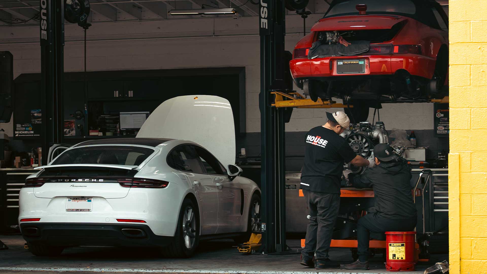 two independent porsche techs pulling the engine of a guards red 930 porsche 911