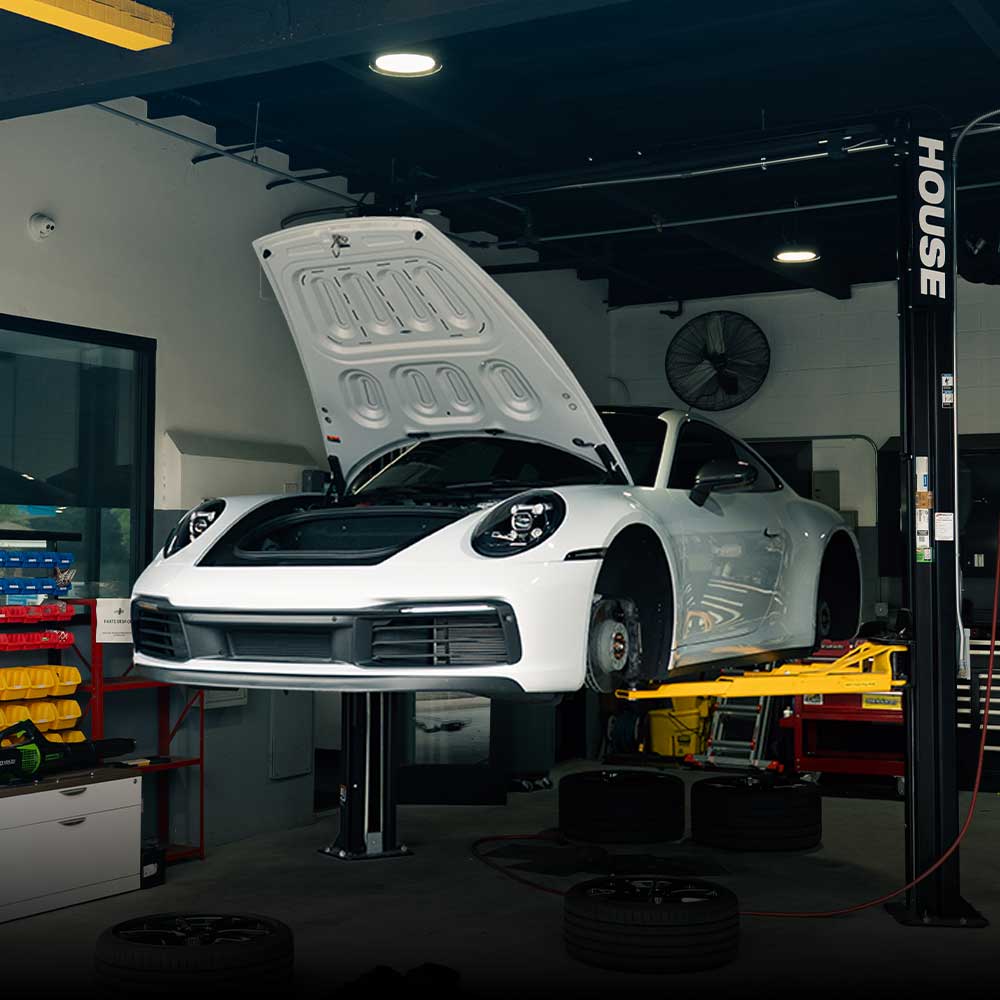 white porsche 992 911 on lift los angeles porsche shop